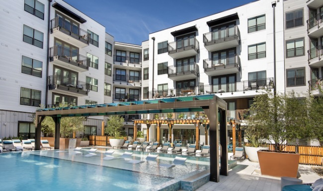 Large sparkling blue pool with a large deck and lounge chairs 